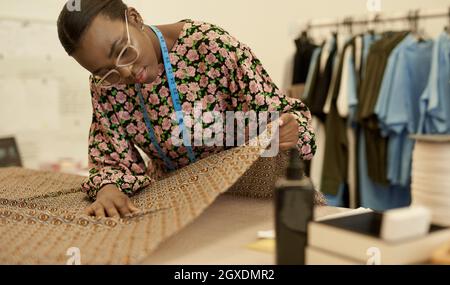 Jeune fille africaine de mode examinant le tissu dans son studio Banque D'Images