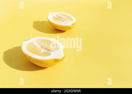 Deux demi-morceaux de citron avec ombre sur fond jaune. Concept de saine alimentation, de voyage ou de vacances Banque D'Images