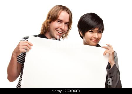 Couple attrayant et diversifié tenant un panneau blanc vierge isolé sur un fond blanc. Banque D'Images