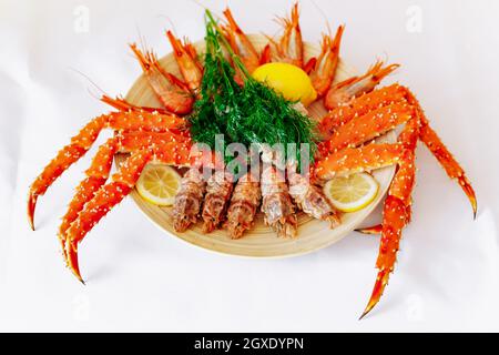 Le crabe royal rouge et les crevettes sur une plaque avec du citron et l'aneth. Fond blanc Banque D'Images