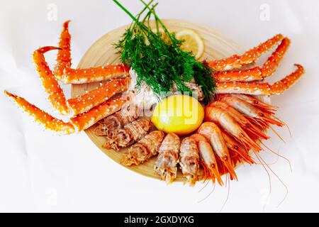 Le crabe royal rouge et les crevettes sur une plaque avec du citron et l'aneth. Fond blanc Banque D'Images