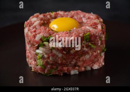 Tartare de boeuf avec œuf brut, et oignons, herbes fraîches. Cuisine française Banque D'Images