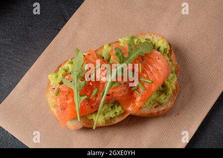 Pain à grains entiers avec pâte d'avocat et saumon, feuilles d'arugula. Banque D'Images