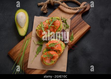 Pain à grains entiers avec pâte d'avocat et saumon, feuilles d'arugula. Banque D'Images