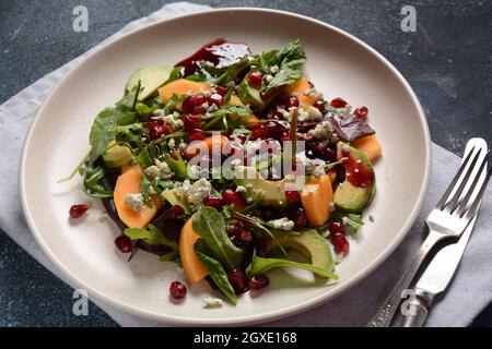 Salade saine persimmon, fromage bleu, épinards, arugula, feuilles de laitue sur plaque blanche Banque D'Images