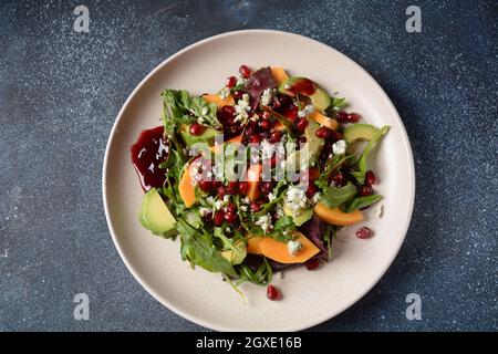 Salade saine persimmon, fromage bleu, épinards, arugula, feuilles de laitue sur plaque blanche Banque D'Images