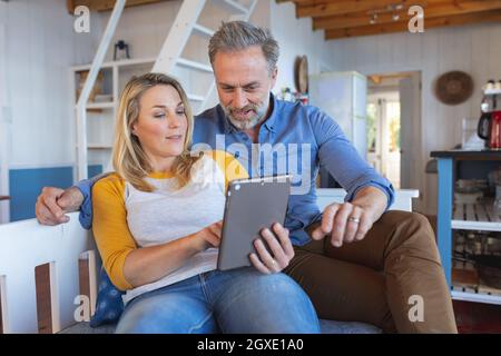 Heureux couple d'âge mûr caucasien faisant appel vidéo dans la cuisine Banque D'Images