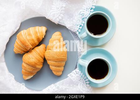 Deux tasses de café avec les croissants sur l'arrière-plan de lacets Banque D'Images