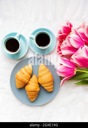 deux tasses de café, croissants et bouquet de tulipes roses, belle matinée. carte de saint-valentin Banque D'Images