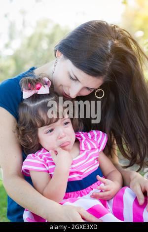 Mixed Race Mère pleurant Consoles sa petite fille à parc. Banque D'Images