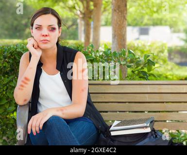 Et bafouées triste Jeune femme assis sur un banc à l'extérieur dans un parc. Banque D'Images