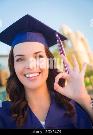 Heureux de son diplôme Mixed Race Woman in Cap and Gown célébrer sur le campus. Banque D'Images