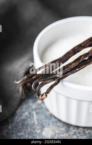 Gousses de vanille. Bâtonnets de vanille et de sucre blanc dans un bol. Banque D'Images