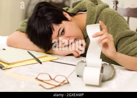 Jeune femme multi-ethnique tourmenter au sujet des calculs financiers dans sa cuisine. Banque D'Images