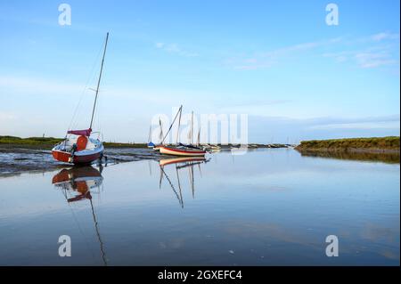 Des voiliers et de petits bateaux de loisirs amarrés sur Morston Creek près de Blakeney point tandis que la marée arrive sur une fin d'après-midi lumineuse. Norfolk, Angleterre. Banque D'Images