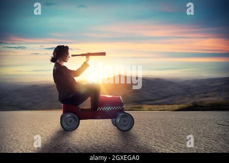 Businesswoman avec télescope sur une voiture rapide à la recherche de nouvelles occasions d'affaires Banque D'Images