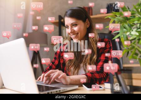 Une femme heureuse peut discuter via un ordinateur portable avec des messages, des discussions et des icônes d'utilisateur Banque D'Images