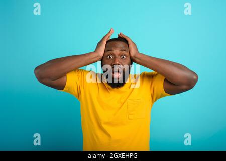 Expression stupéfaite et choquée d'un garçon noir sur le cyan arrière-plan Banque D'Images