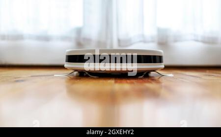 Robot-aspirateur et nettoyage à la vadrouille, salle de séjour, près du sol. Appareil moderne et intelligent pour un entretien quotidien. Banque D'Images