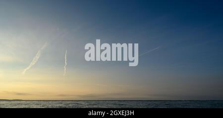 Vue panoramique de la basse lumière du soleil sur la côte de la mer du Nord de Norfolk depuis Blakeney point avec contrailles dans le ciel bleu. Angleterre. Banque D'Images