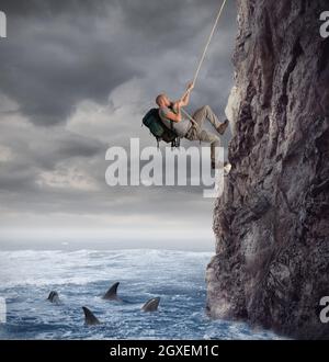 Explorer grimpe une montagne avec le risque de tomber sur la mer profonde avec les requins Banque D'Images
