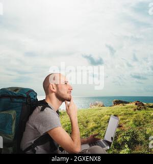 Explorer homme prévoit un nouveau voyage à une plage tropicale avec son ordinateur portable Banque D'Images