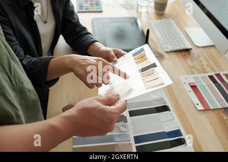 L'un des deux designers qui pointe vers un échantillon textile de couleur gris pâle Banque D'Images