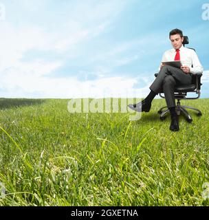 Un homme d'affaires qui profite d'une journée de détente dans un champ vert Banque D'Images
