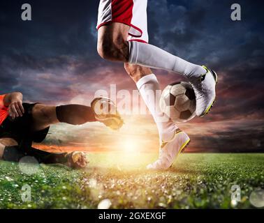 Joueurs de football avec sockcerball au stade illuminé pendant le match Banque D'Images