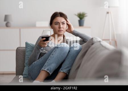 Triste frustré jeune femme caucasienne avec un verre de vin souffrant de dépression, de stress et de surtravail à la maison Banque D'Images