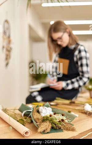 beau bouquet d'automne de fleurs sèches sur table en bois et jolie jeune femme fleuriste sur fond Banque D'Images