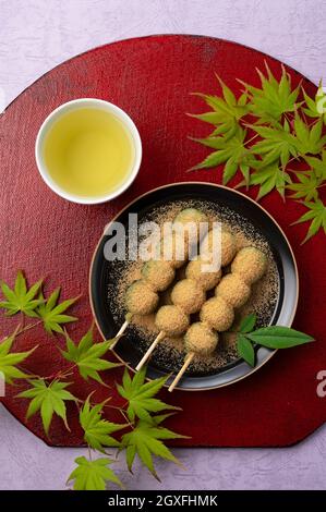 Boulettes d'herbe et thé vert servis sur une assiette noire placée sur un plateau rouge boulettes japonaises. Vue de directement au-dessus. Banque D'Images