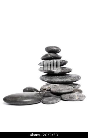 Galets noirs ou pierres zen empilées les unes sur les autres comme une pyramide, isolées sur fond blanc. Harmonie, équilibre et méditation, spa, massage, Banque D'Images