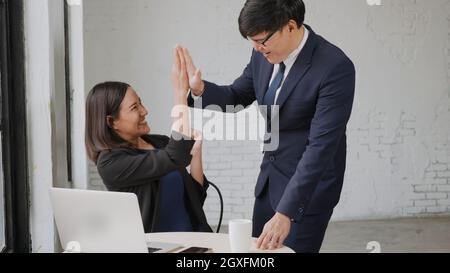 Oui ! Heureux excité réussi, homme d'affaires asiatique et femme sourire station de travail triomphant avec les mains levées avec ordinateur portable, femme succès Banque D'Images