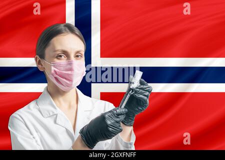 La jeune fille prépare la vaccination contre le fond du drapeau norvégien. Concept de vaccination Norvège. Banque D'Images