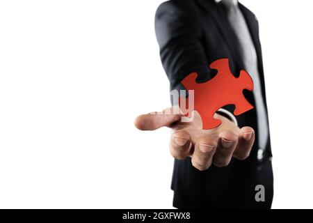 Businessman complete a puzzle inserting a missing piece Stock Photo