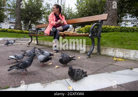 Détail de la jeune femme nourrissant des oiseaux dans la ville Banque D'Images