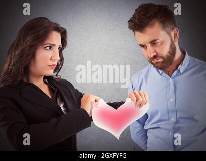Une femme en colère déchirant un cœur en papier rouge Banque D'Images