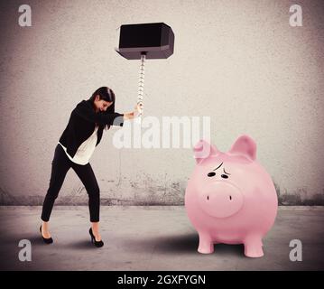 Une femme casse avec un marteau une pigegibank Banque D'Images