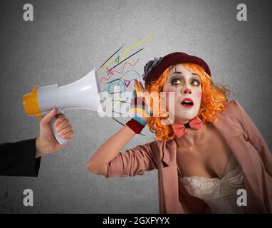 Clown entend un mégaphone avec une expression d'alerte Banque D'Images