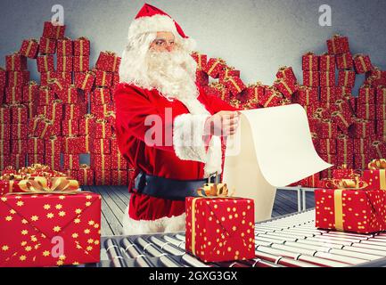 Rendu 3D santa claus vérifier sur la liste des boîtes cadeaux de Noël et enveloppé sur le rouleau de convoyeur Banque D'Images