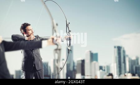 Les hommes d'affaires en concurrence avec l'arc et les flèches pour atteindre et atteindre de nouvelles cibles dans un toit de gratte-ciel Banque D'Images