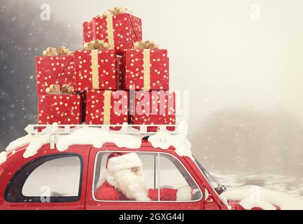 Le Père Noël conduit une voiture rouge pleine de cadeau de Noël Banque D'Images