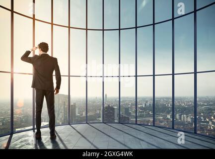 Homme d'affaires apprécie son succès professionnel et regarde la vue sur la ville. Supports mixtes Banque D'Images