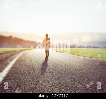 L'homme marche sur une route inconnue pour une nouvelle aventure au coucher du soleil. Concept de nouvelles opportunités Banque D'Images