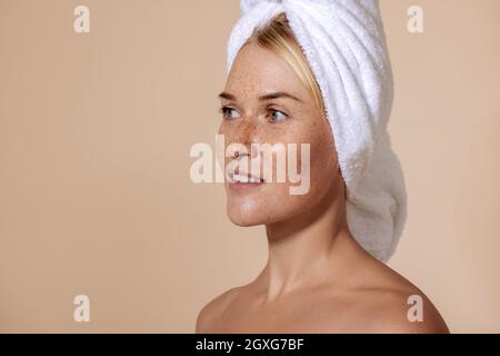 Portrait d'une jeune femme confiante aux taches de rousseur. Studio photo d'une belle femme avec une serviette sur la tête. Banque D'Images