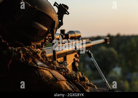 Les forces spéciales tirper avec un fusil de grand calibre à la recherche et à la mort de l'ennemi. Vue arrière coucher de soleil ciel arrière-plan Banque D'Images