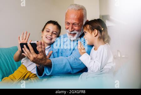 Le grand-père heureux se remet du coronavirus est visité par ses petits-enfants Banque D'Images