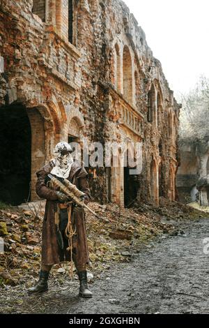 Post-apocalypse nucléaire. Seul survivant en lambeaux et masque à gaz sur les ruines de la ville détruite Banque D'Images