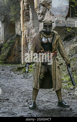 Post-apocalypse nucléaire. Seul survivant en lambeaux et masque à gaz sur les ruines de la ville détruite Banque D'Images